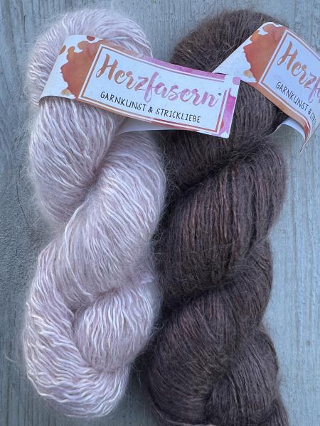Zwei Stränge handgefärbte Wolle im Set: links ein Strang in Puderrosé (Herzfasern No. 50), rechts ein Strang in Schokobraun (Herzfasern No. 11).“ 	•	Struktur im Shoptext: klare Absätze, Bulletpoints bei Zusammensetzung/Pflege. 	•	Farbkontraste: Foto zeigt